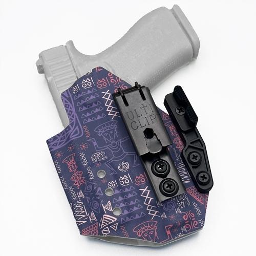 Custom Appendix Inside the Waistband (AIWB) KYDEX holster for Glock 43X MOS with Streamlight TLR-7 sub. The holster features a dark purple background with pink and light purple tribal-style geometric patterns and figures. It is equipped with UltiClip XL, Modwing concealment claw