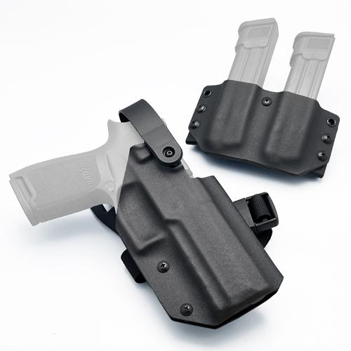 A detailed angled overhead view on a white background showing a black KYDEX Outside the Waistband (OWB) Level 2 retention duty holster with a TRS Duty Drop mount and leg strap for SIG Sauer P320 M17 Full Size pistol, positioned next to a matching black KYDEX double magazine pouch. (ซองปืน KYDEX และซองแม็กคู่ สำหรับ SIG Sauer P320 Full Size / M17e)